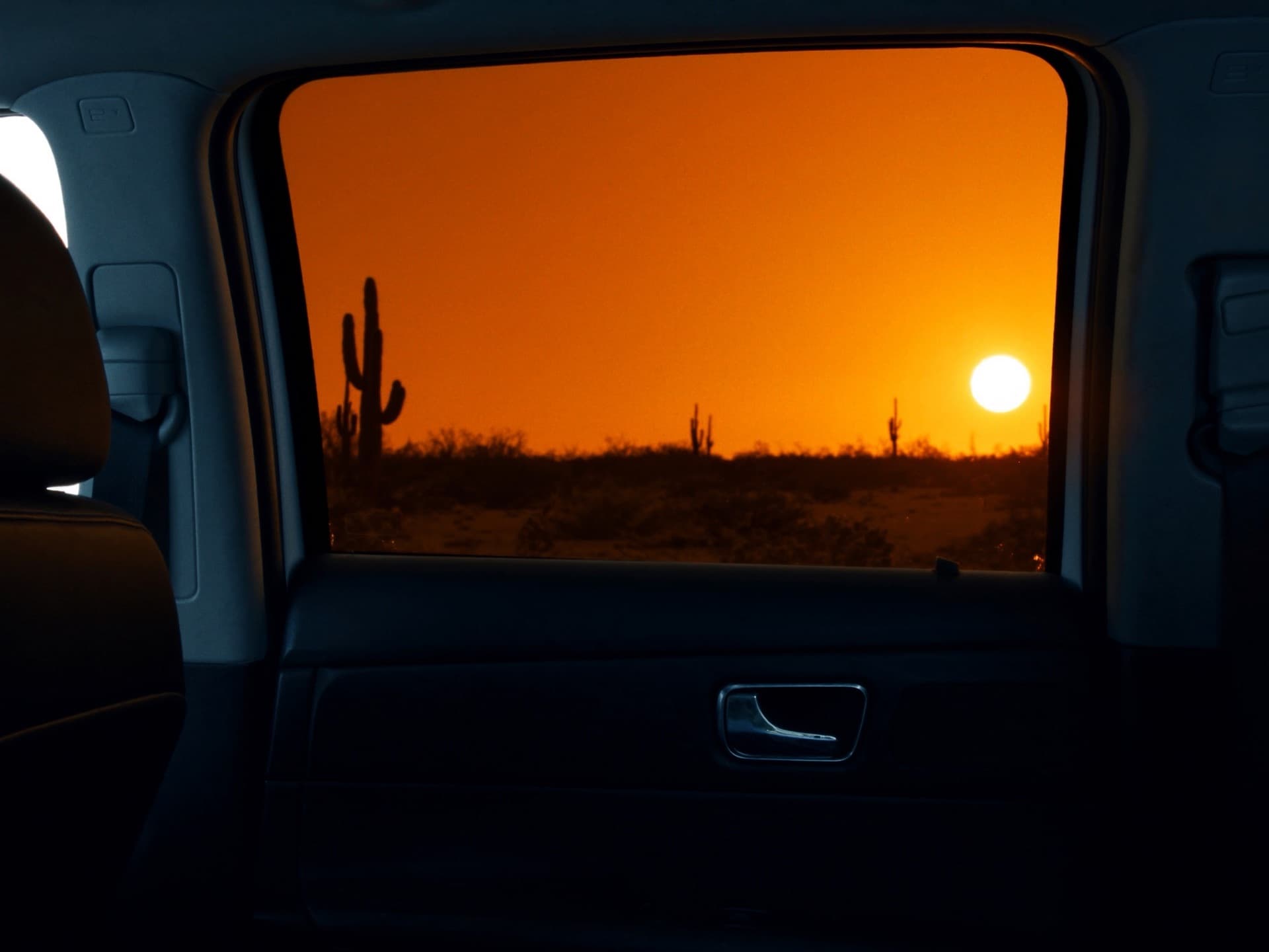 Looking out from a shaded car interior through a window at the desert sun