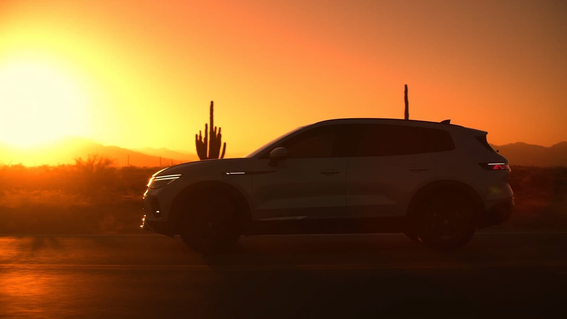 SUV with dark tinted windows on a desert road at sunset, saguaro cactus behind